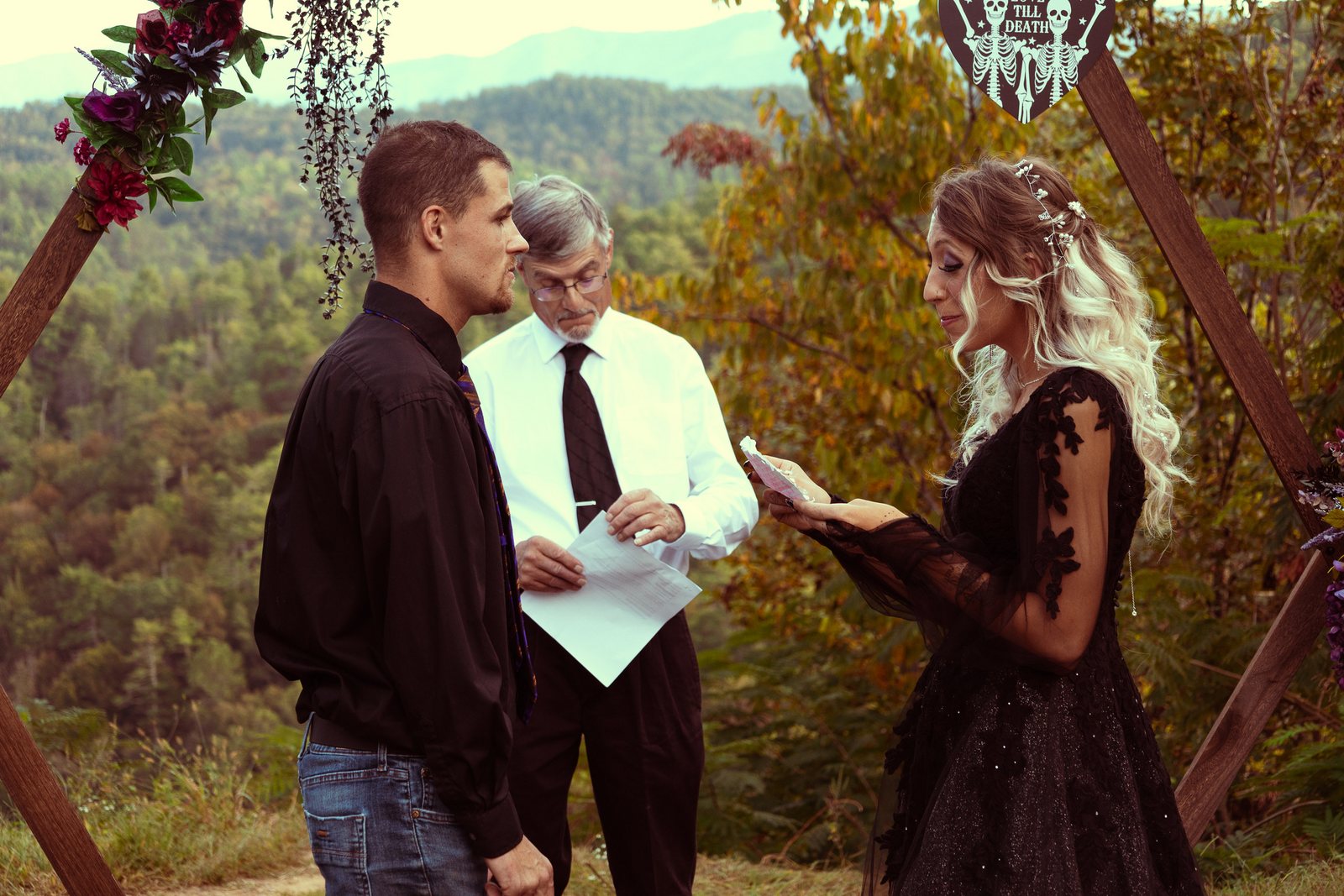 A couple exchanging vows beneath a floral arch